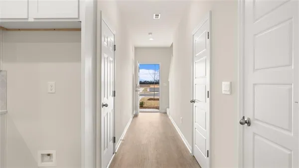 a view of a hallway with wooden floor and a bathroom