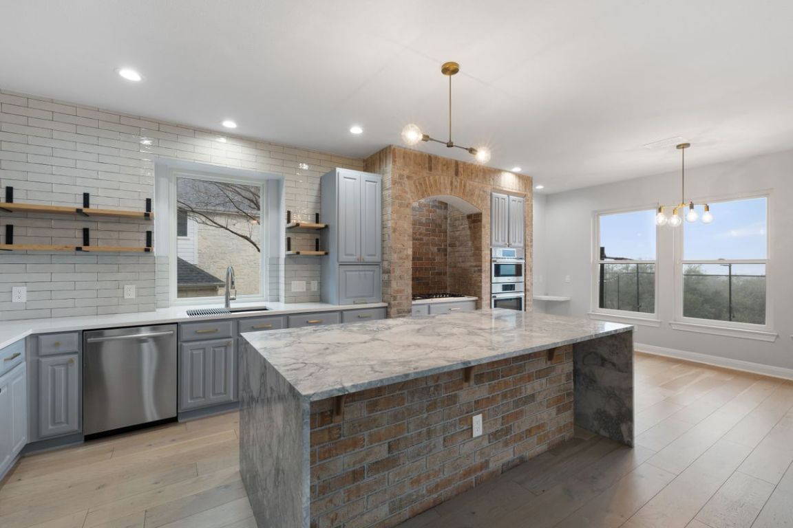 Kitchen with gray cabinets, backsplash, open shelves, light stone counters, and recessed lighting