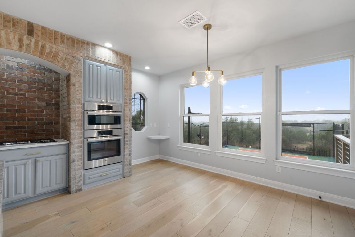 2137 Rivina Drive Austin, TX 78733 - Photo 3 of 39 Kitchen with Greenbelt views featuring gray cabinets, pendant lighting, light wood-style flooring, recessed lighting, and a chandelier