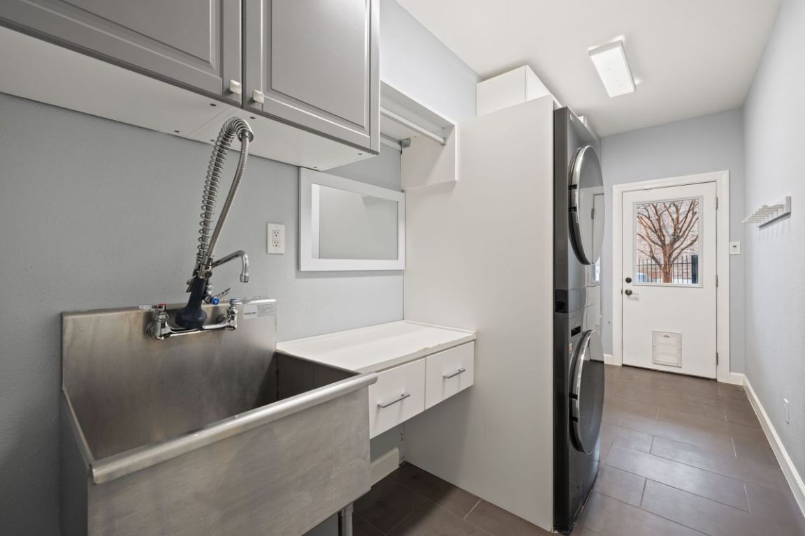 2137 Rivina Drive Austin, TX 78733 - Photo 35 of 39 Washroom featuring stacked washer and clothes dryer, dark tile patterned floors, and cabinet space