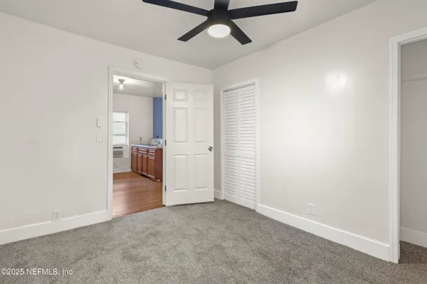an empty room with chandelier fan and windows