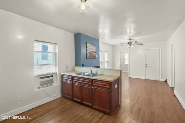 a view of a kitchen with a stove cabinets a ceiling fan and wooden floor