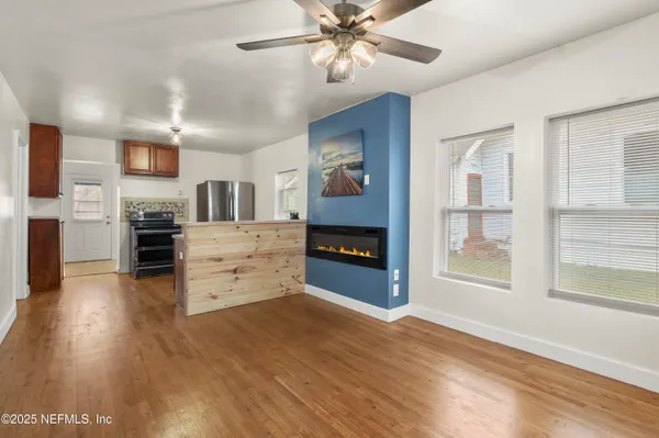 a view of a kitchen with a stove cabinets a ceiling fan and wooden floor