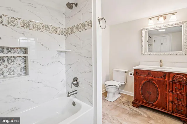 a bathroom with a bathtub sink vanity mirror and toilet