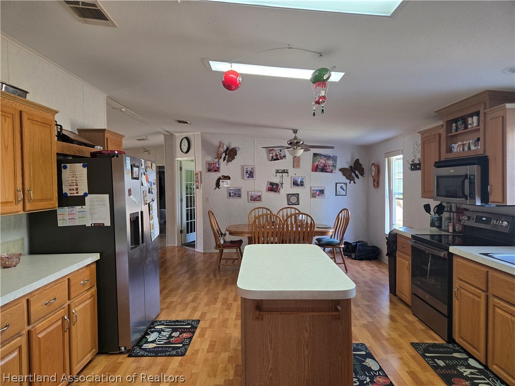 504 Thunderbird Hill Road Sebring, FL 33872 - Photo 7 of 35 a living room with stainless steel appliances furniture a rug and a kitchen view