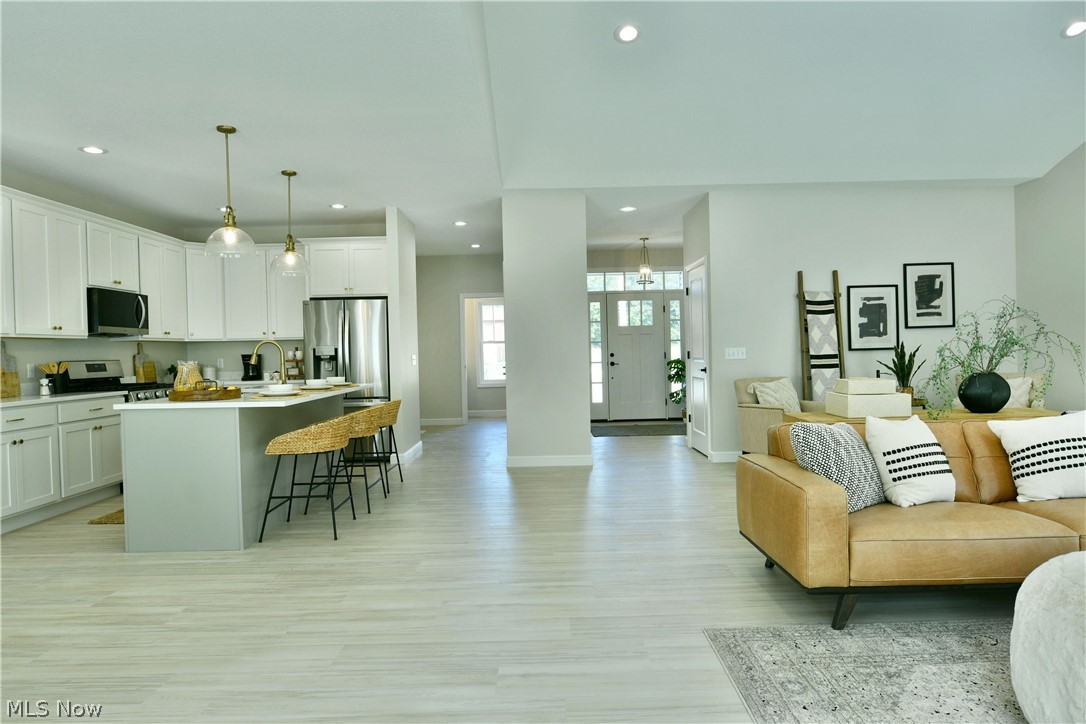 4780 State Rte 5 Cortland, OH 44410 - Photo 19 of 50 Spacious open-concept living area featuring light wood-finish flooring, recessed lighting, and a kitchen with white cabinetry, stainless steel appliances, and a central island with pendant lighting