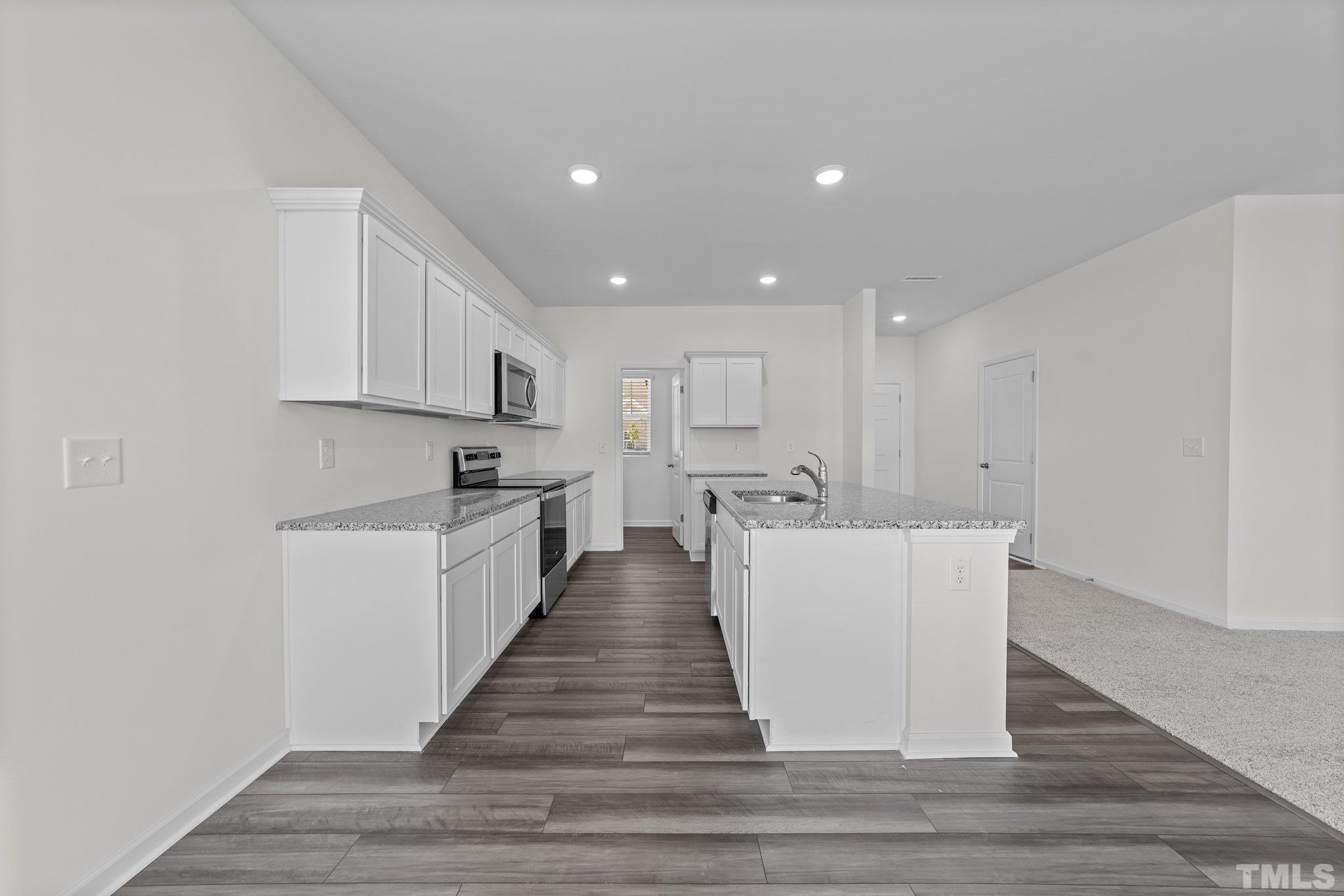 200 Miles Drive Pikeville, NC 27863 - Photo 8 of 34 a large white kitchen with kitchen island a sink wooden floor and a refrigerator