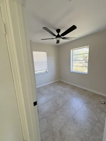 an empty room with windows and fan