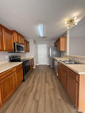 a large kitchen with cabinets wooden floor and stainless steel appliances