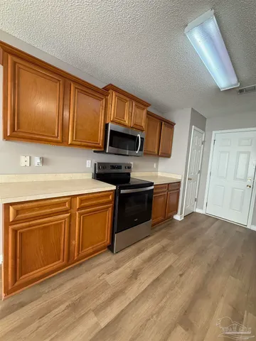 a kitchen with granite countertop wooden cabinets a stove top oven and stainless steel appliances