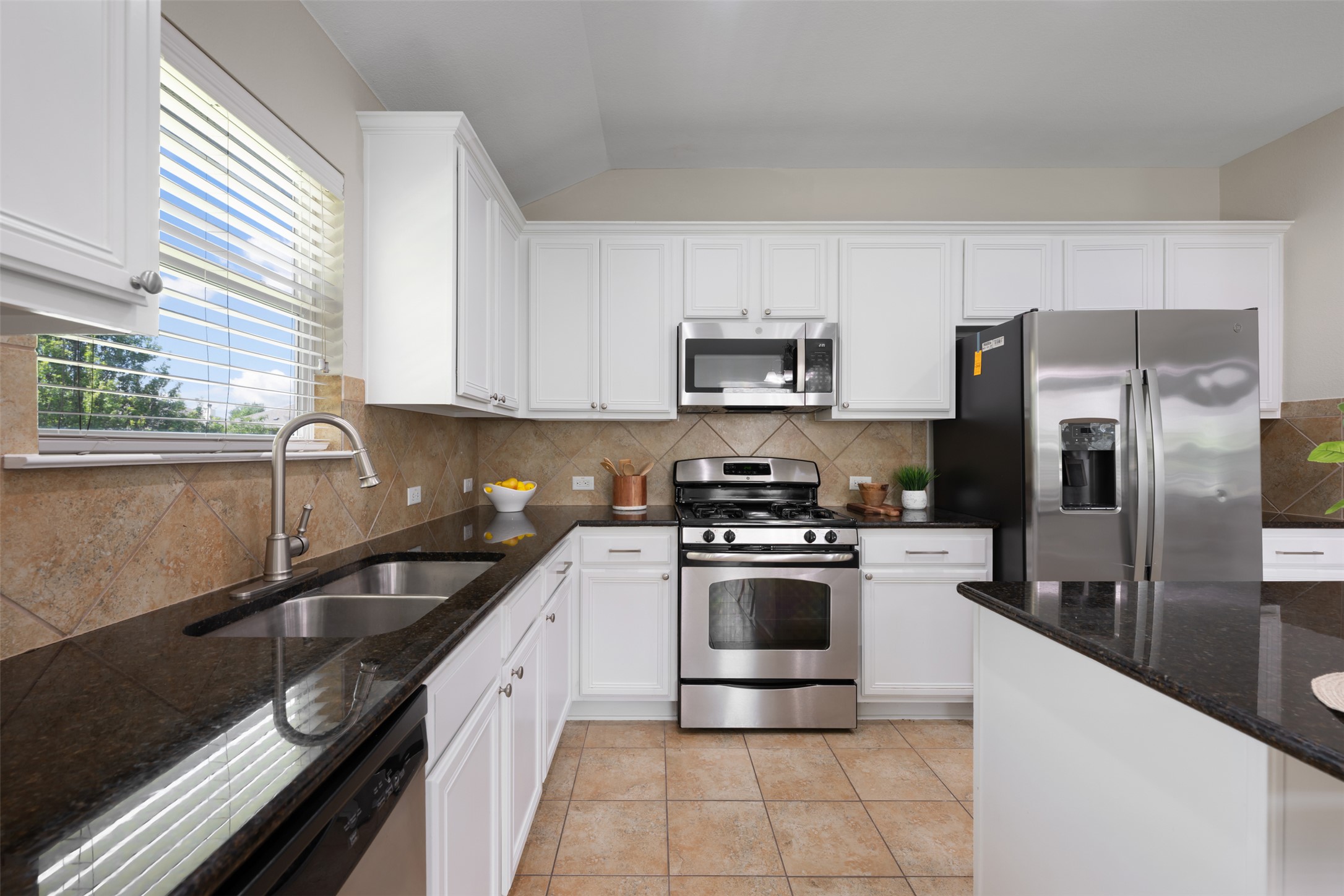 18820 Edinburgh Castle Road Pflugerville, TX 78660 - Photo 14 of 37 a kitchen with stainless steel appliances a sink a stove a microwave and a refrigerator