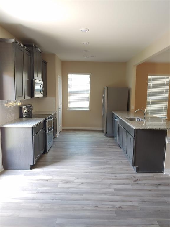 280 Moonstone Way Princeton, TX 75407 - Photo 11 of 17 Kitchen with light stone counters, light hardwood / wood-style floors, dishwasher, range, and sink