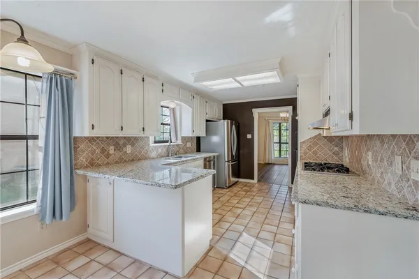 a kitchen with granite countertop a sink a stove a refrigerator and cabinets
