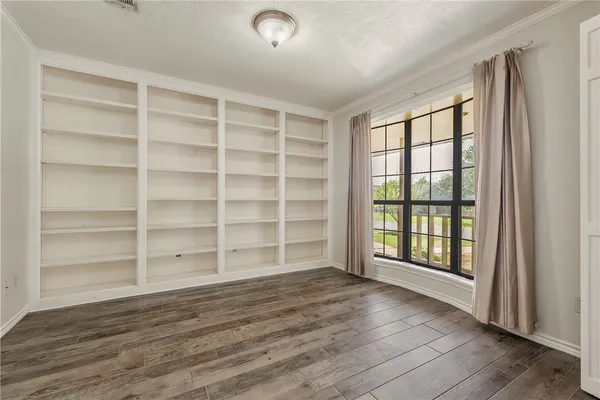a view of an empty room with a window and wooden floor