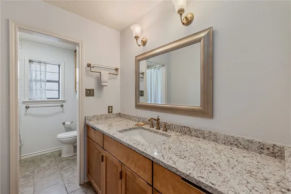 a bathroom with a granite countertop sink toilet and mirror