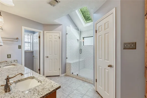 a bathroom with a granite countertop sink a mirror and shower