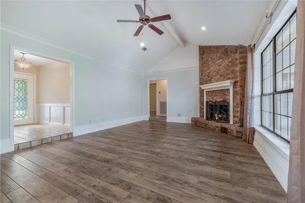 a view of empty room with fireplace and wooden floor