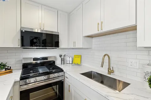 a kitchen with stainless steel appliances granite countertop grey cabinets a stove a sink and dishwasher