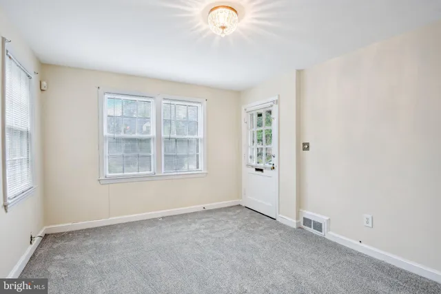 an empty room with windows and chandelier fan