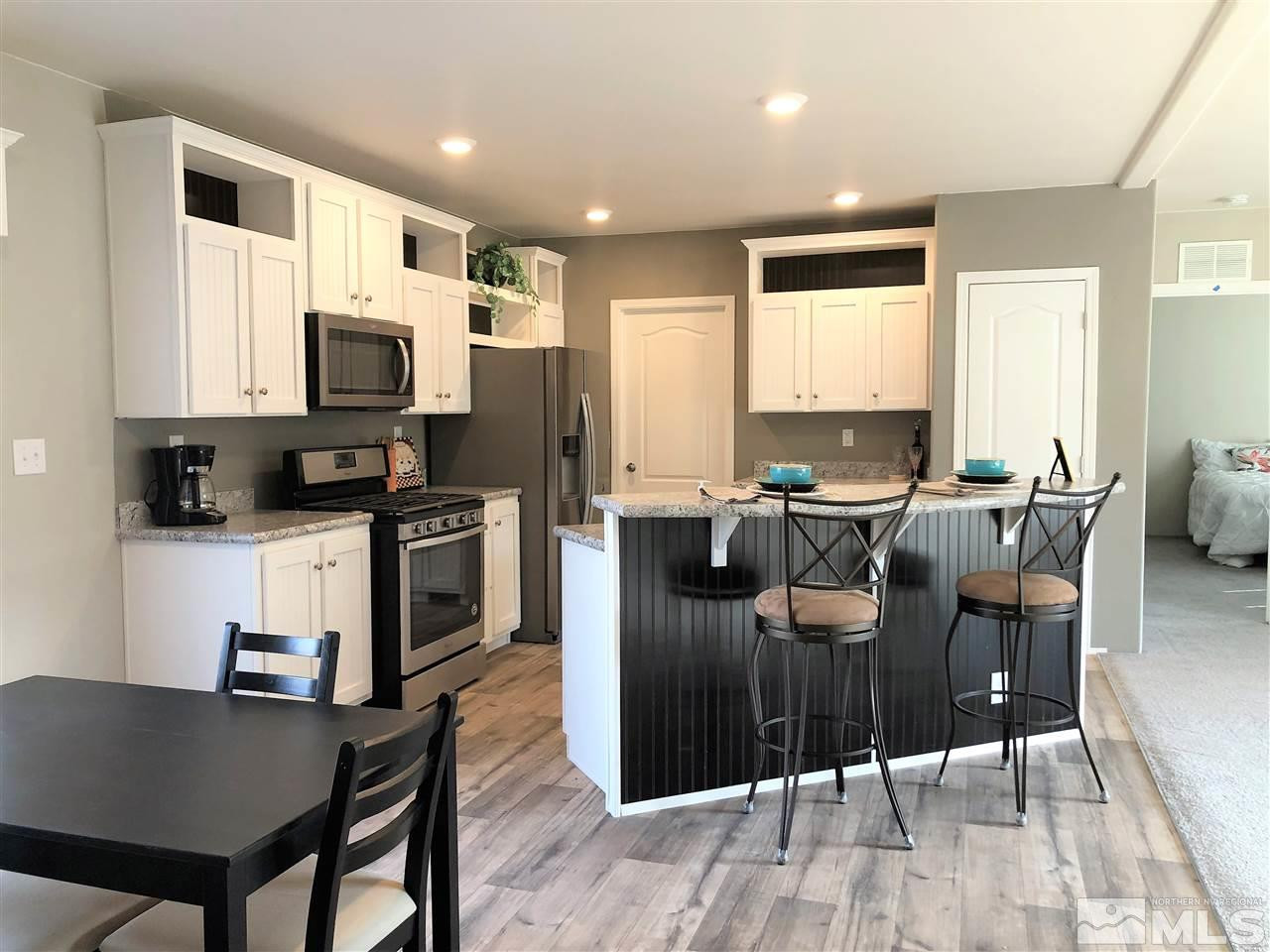 15380 Tuxon Way Reno, NV 89521 - Photo 1 of 25 a kitchen with granite countertop a stove top oven a sink dishwasher a dining table and chairs with wooden floor