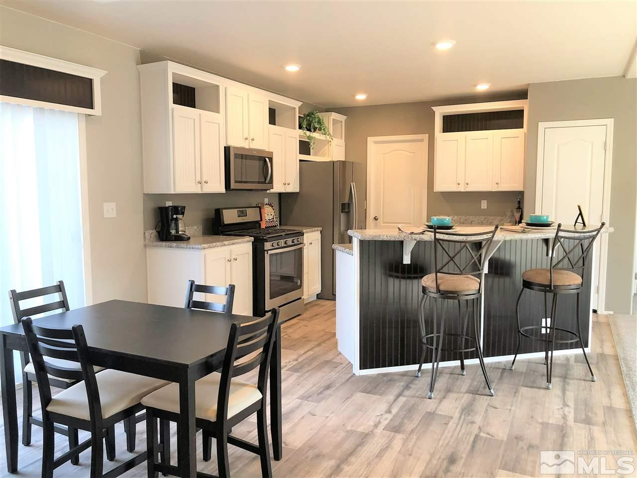 15380 Tuxon Way Reno, NV 89521 - Photo 4 of 25 a kitchen with stainless steel appliances kitchen island granite countertop a dining table chairs and a refrigerator