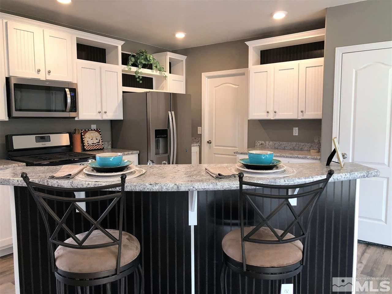 15380 Tuxon Way Reno, NV 89521 - Photo 6 of 25 a kitchen with stainless steel appliances a table chairs and a refrigerator