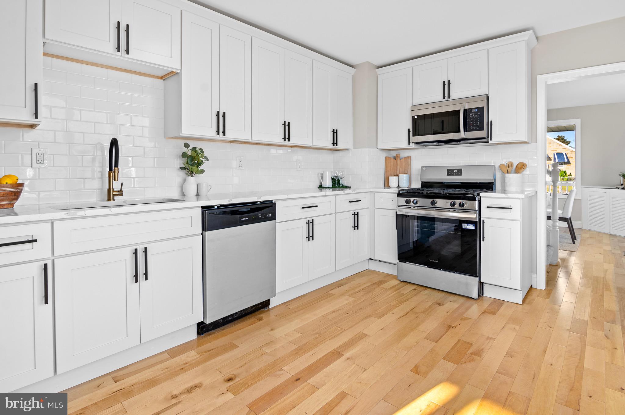 a kitchen with cabinets stainless steel appliances a sink and wooden floor