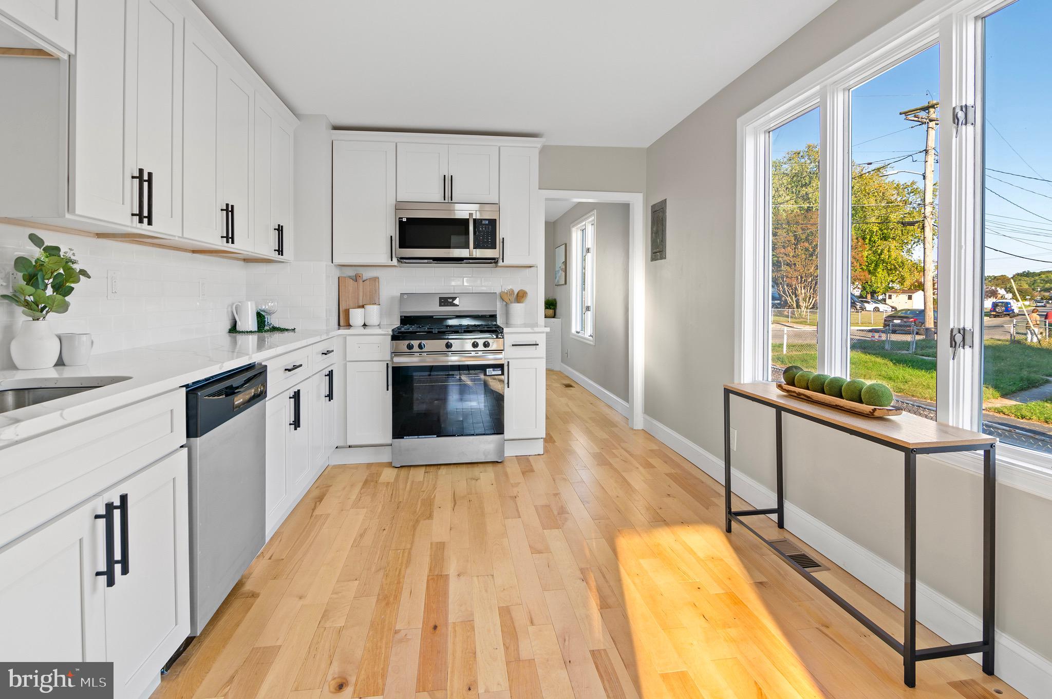 1237 Willow Road Dundalk, MD 21222 - Photo 17 of 29 a large kitchen with stainless steel appliances granite countertop a lot of counter space and wooden floors