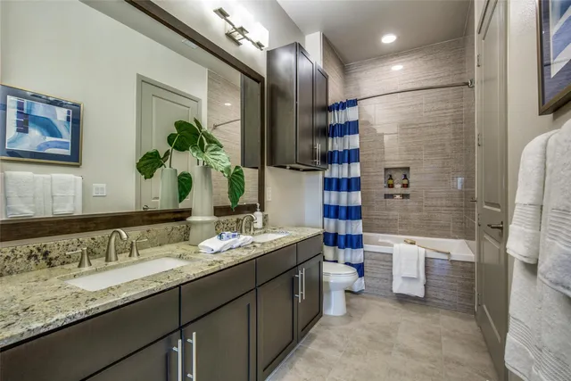 a bathroom with a granite countertop sink a toilet a shower and a mirror