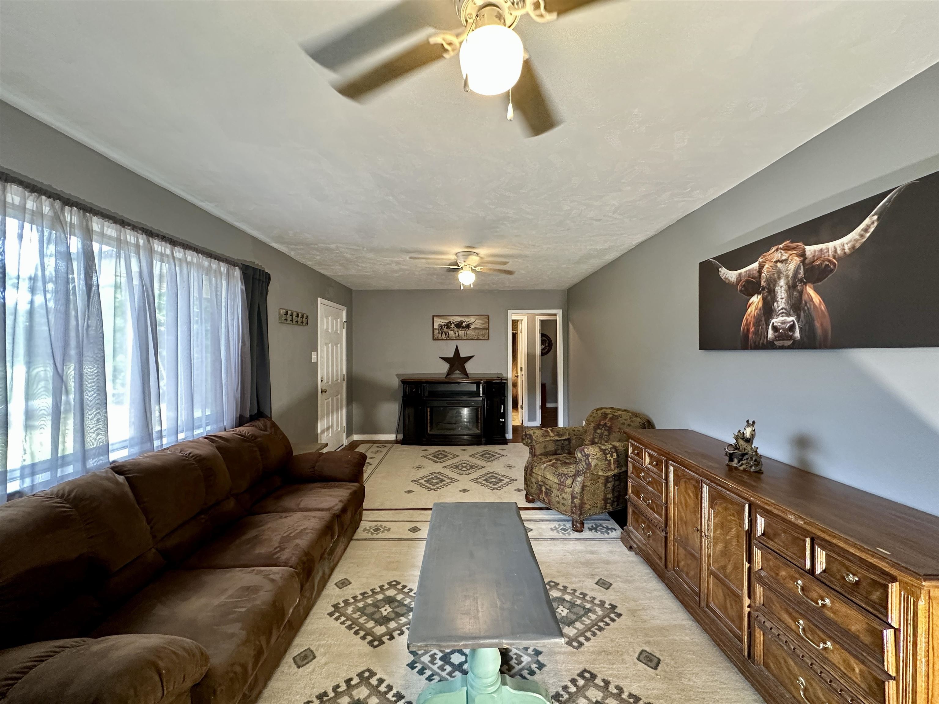 2505 Pittman Road Somerville, TN 38068 - Photo 5 of 23 Spacious living area featuring neutral-toned walls, two ceiling fans with integrated lighting, and a large window with sheer drapes