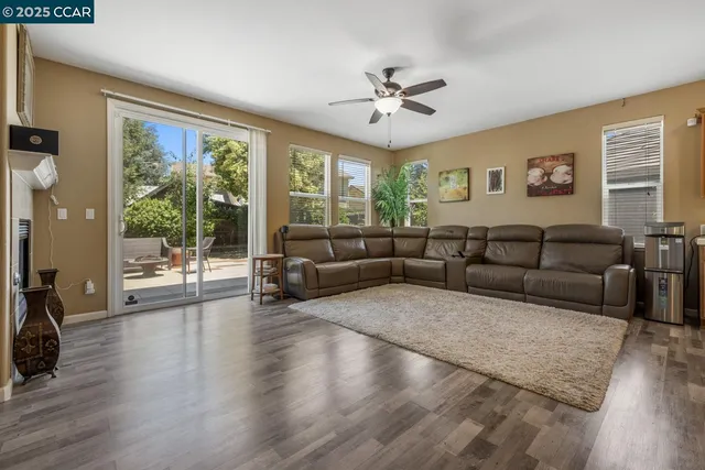 a living room with furniture kitchen view and a wooden floor