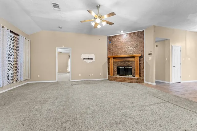 an empty room with chandelier fan and fireplace