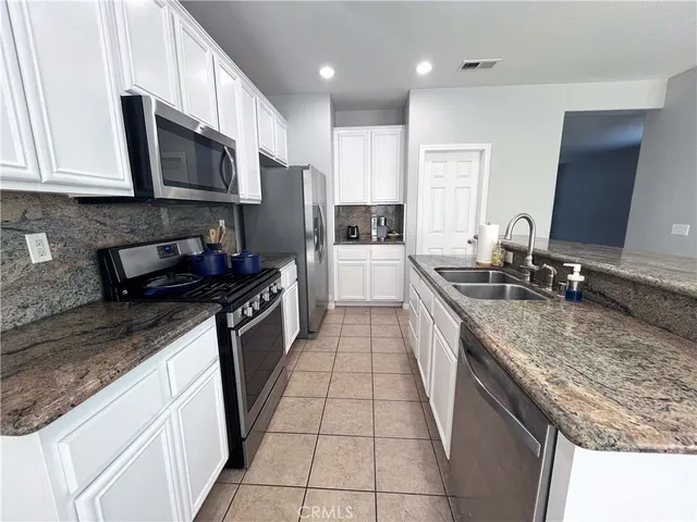 a kitchen with stainless steel appliances granite countertop a sink a stove top oven a refrigerator and a granite counter tops