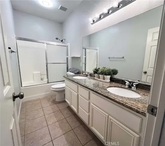a bathroom with a granite countertop sink a toilet a mirror and shower