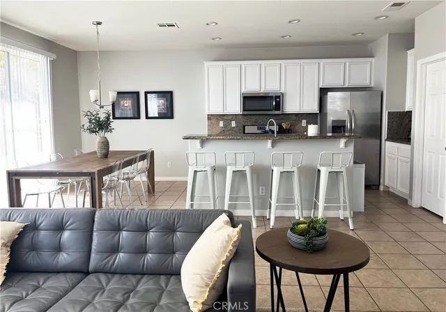 a kitchen with stainless steel appliances granite countertop a table chairs and a living room view