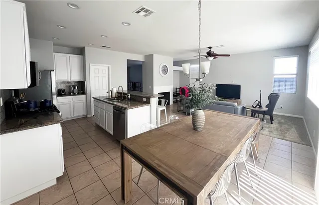 a kitchen with a stove a refrigerator a sink dishwasher a dining table and chairs with wooden floor