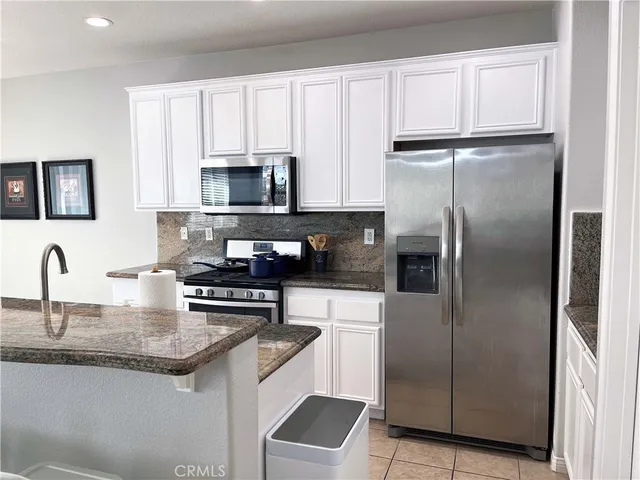 a kitchen with granite countertop a refrigerator stove and microwave