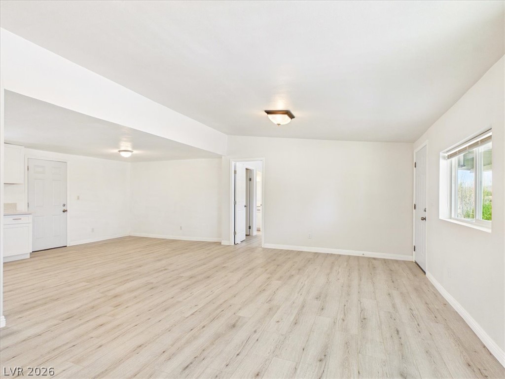 4081 Retread Road Pahrump, NV 89048 - Photo 10 of 98 A spacious, naturally illuminated room boasts crisp white walls and elegant wood flooring, creating an inviting atmosphere.
