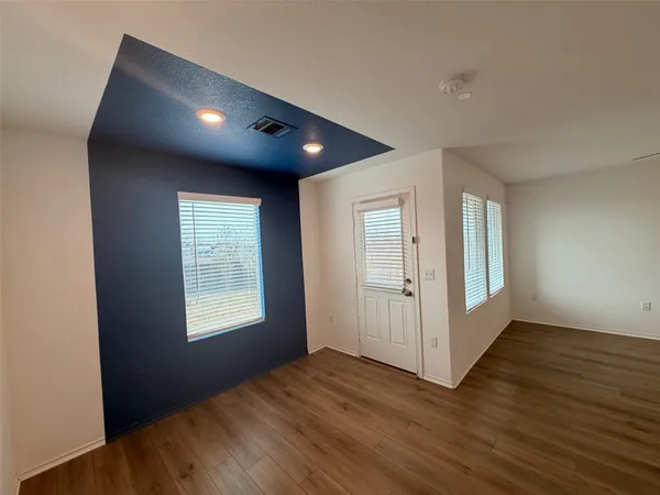 an empty room with wooden floor and windows