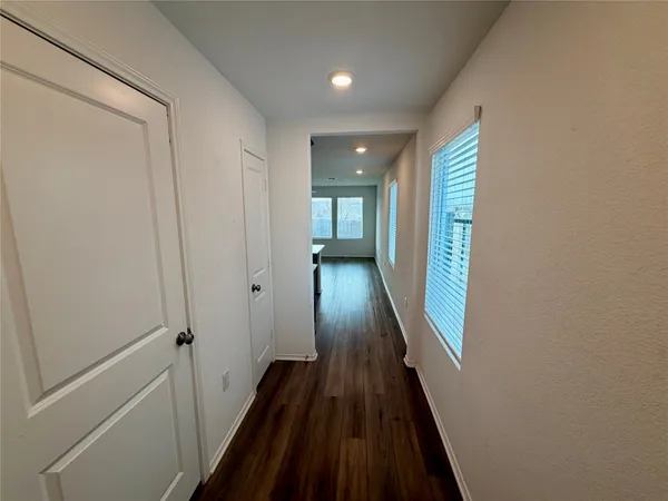 a view of a hallway with wooden floor and a bathroom