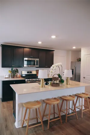 a kitchen with stainless steel appliances granite countertop a table chairs microwave and sink