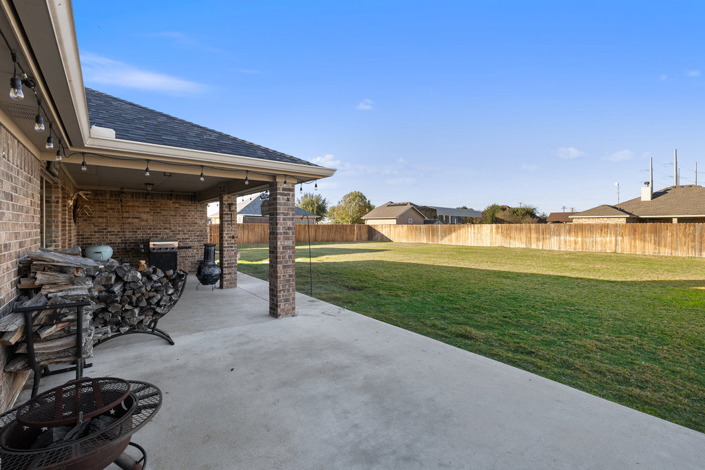 153 Ranger Boulevard Salado, TX 76571 - Photo 32 of 40 a view of a patio with table and chairs under an umbrella next to a yard