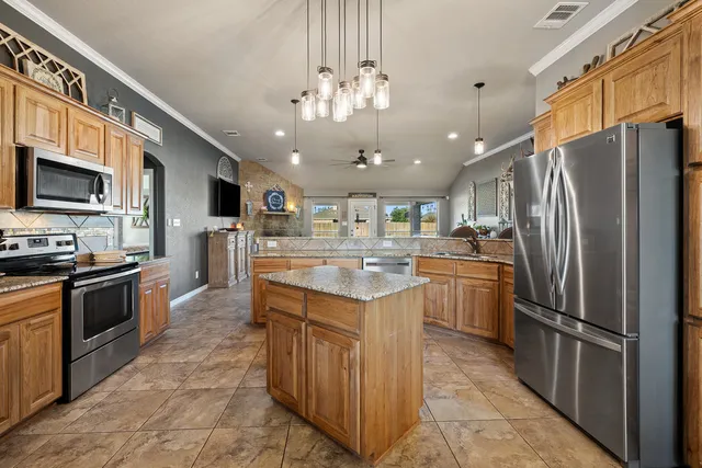 a kitchen with kitchen island stainless steel appliances a sink stove top oven and refrigerator