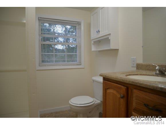 40 Lyle Street Tryon, NC 28782 - Photo 10 of 16 a bathroom with a granite countertop toilet a sink and a window