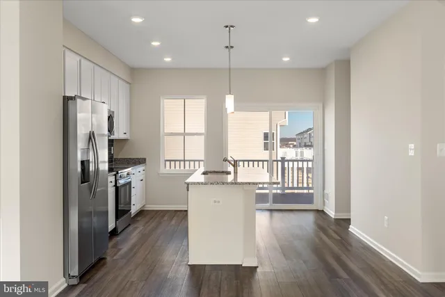 a kitchen with stainless steel appliances granite countertop a refrigerator a sink a stove and wooden floors