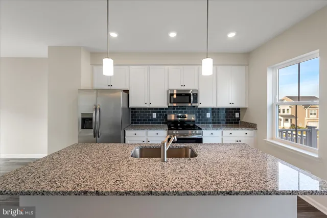 a kitchen with stainless steel appliances granite countertop a sink refrigerator and microwave
