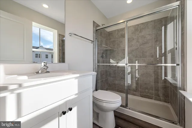 a bathroom with a shower sink vanity mirror and toilet