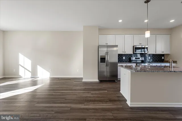 a kitchen with stainless steel appliances granite countertop a refrigerator a stove a sink and a microwave