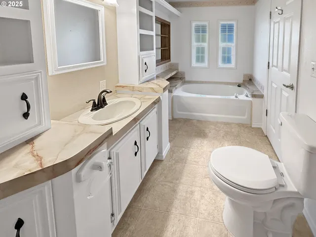 a bathroom with a granite countertop sink mirror bathtub and toilet