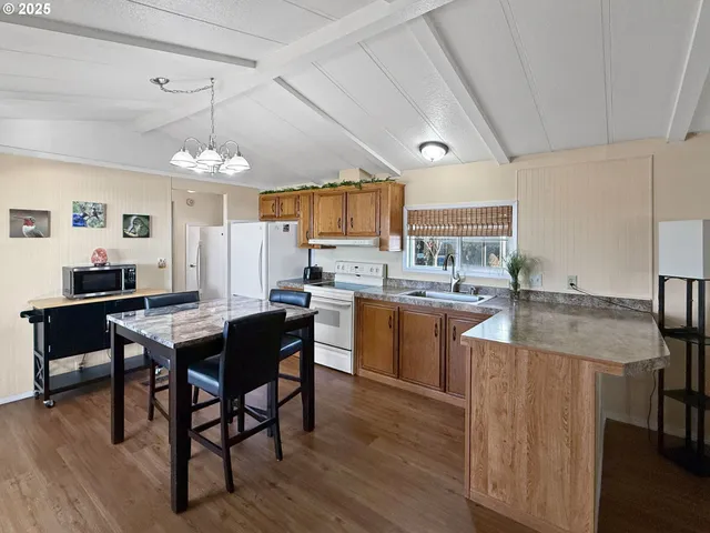a kitchen with stainless steel appliances granite countertop a sink dishwasher a stove refrigerator and cabinets with wooden floor